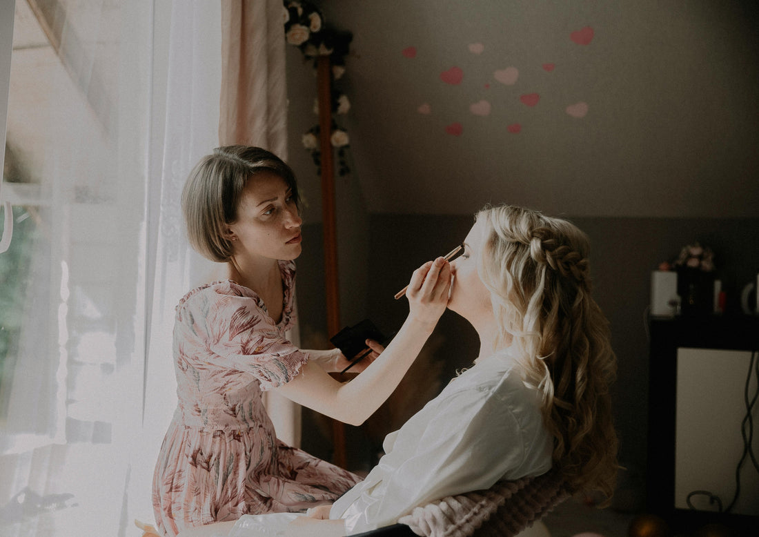 Professional wedding makeup artist applying setting spray to bride for long-lasting flawless makeup